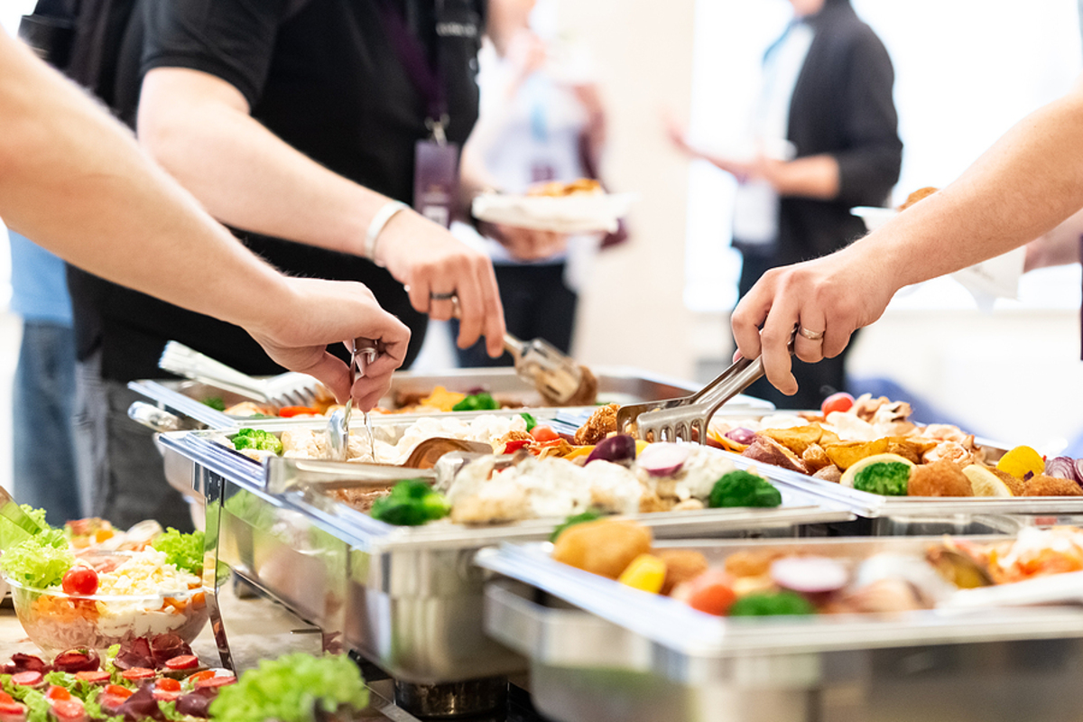 Close up of hands scooping food. Buffet catering meal concept.